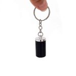 Cendrier porte-clés fermé cylindrique noir en acier inoxydable, capuchon argenté brillant et compact.