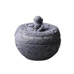 Cendrier de table en céramique grise, design lune texturée avec figurine astronaute.
